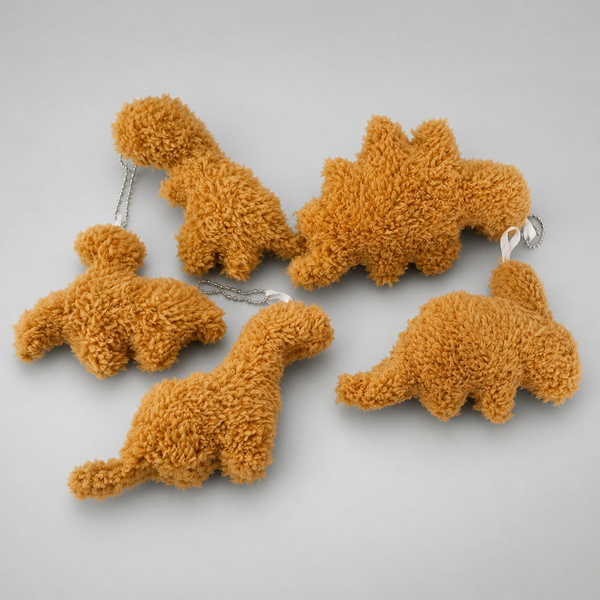 Five dino nugget plush keychains: T. rex, Pterosaur, Stegosaurus, Brontosaurus and Triceratops