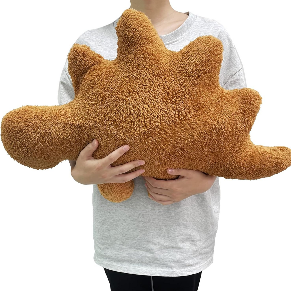 Person holding a large Stegosaurus dinosaur nugget plush pillow with spiky back plates